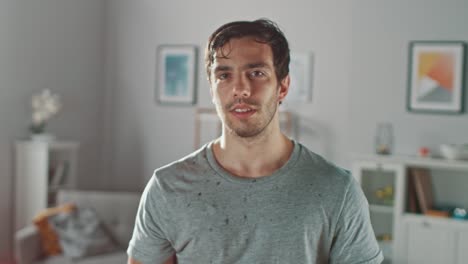 Sweating-Muscular-Athletic-Fit-Man-in-Grey-Outfit-is-Posing-After-a-Workout-at-Home-in-His-Spacious-and-Sunny-Living-Room-with-Minimalistic-Interior.