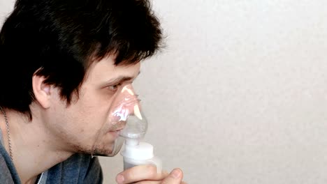 Verwenden-Sie-Vernebler-und-Inhalator-für-die-Behandlung.-Junger-Mann-durch-Inhalator-Maske-einatmen.-Seitenansicht.