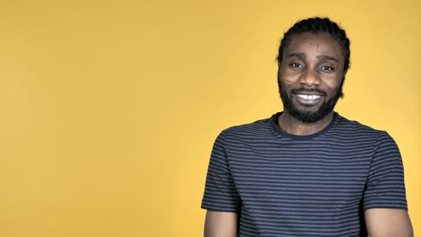 Casual-African-Man-Pointing-with-Finger-on-Side,-Yellow-Background