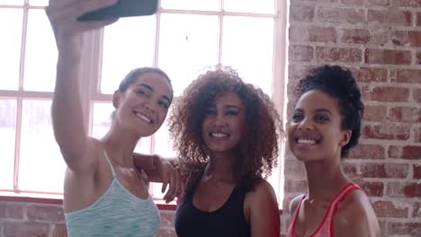 Cheerful-female-friends-taking-self-portrait-at-gym