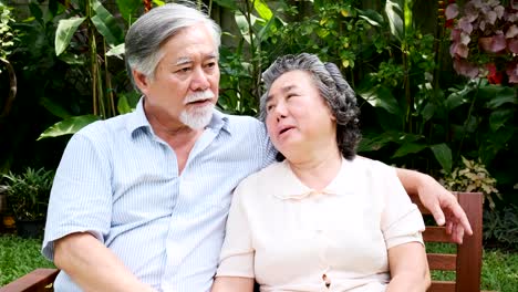 Senior-pareja-sentado-y-hablando-juntos-en-el-jardín-de-casa.