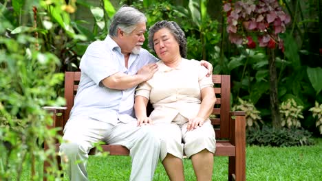 Senior-pareja-sentada-y-consolando-juntos-en-el-jardín-de-casa.