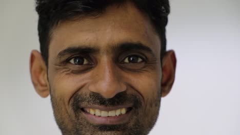 Closeup-of-Indian-man-looking-at-camera-pov-seriously-turns-sideways-and-then-turns-back-and-starts-to-have-a-big-toothy-smile