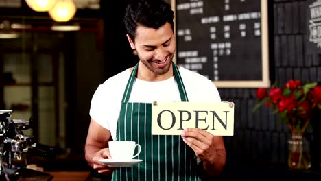 Smiling-waiter-holding-sign-and-coffees-cup