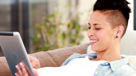 Schwangere-Frau-liegend-auf-der-Sofa-mit-Tablet-während