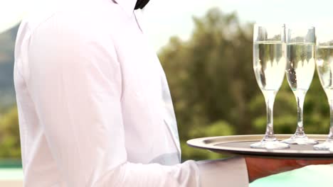 Smiling-waiter-holding-champagne-glasses