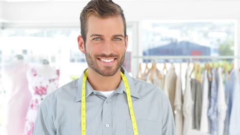 Handsome-fashion-designer-holding-a-scissors-smiling-at-camera