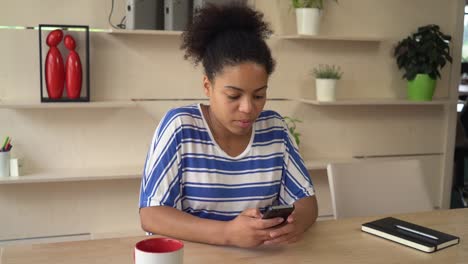 Mixed-race-young-woman-texting-sms-on-the-smartphone