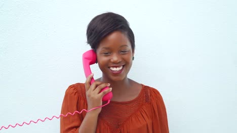 Smiling-happy-young-woman-talking-on-the-pink-telephone