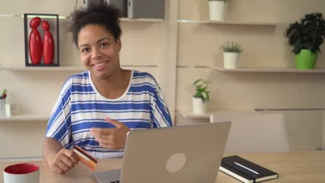 Happy-woman-dancing-with-credit-card-in-the-room-in-front-of-computer