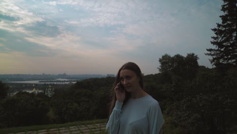 A-girl-in-a-light-jacket-and-standing-in-the-yard-talking-on-the-phone