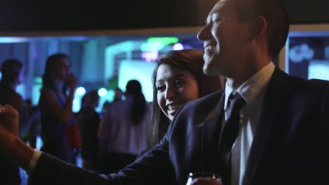 Well-dressed-young-man-and-woman-at-a-nightclub-take-a-selfie-together-with-a-cell-phone