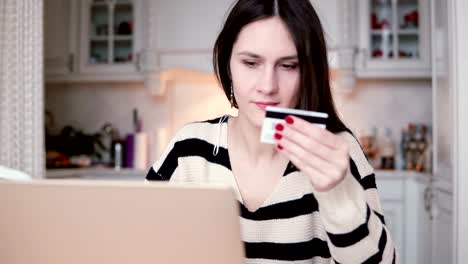 Attractive-young-smiling-woman-uses-plastic-credit-card-shopping-online-with-laptop.-slider-to-the-right