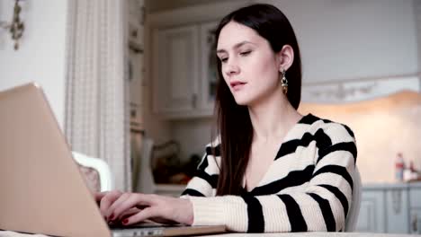 Retrato-de-una-hermosa-joven-morena-utiliza-laptop-en-un-comedor-luminoso