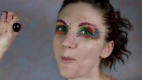 4k-Shot-of-a-Woman-with-Multicoloured-Make-up-Eating-Cherry