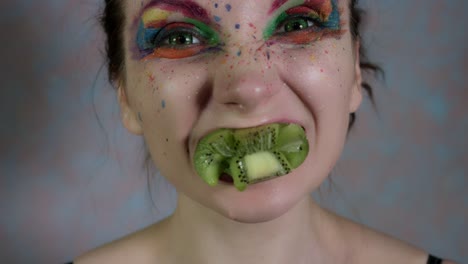 4-tiro-de-k-de-una-mujer-con-maquillaje-multicolor-exprimir-un-Kiwi-en-boca