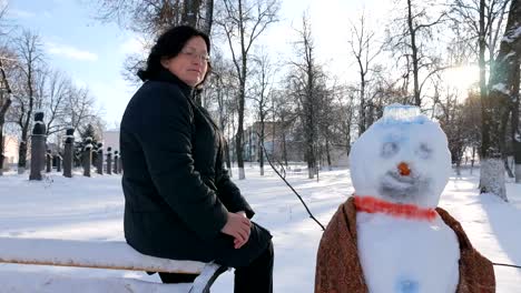 Joven-mujer-edificio-muñeco-de-nieve-en-el-parque.-En-el-invierno