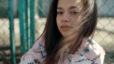 Joven-hermosa-mujer-usando-chaqueta-bomber-posando-sobre-la-cerca-de-metal.