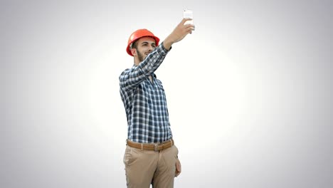 Trabajador-de-la-construcción-usando-el-teléfono-para-tomar-selfies-sobre-fondo-blanco