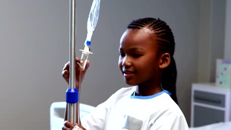 Portrait-of-sick-girl-holding-iv-drip-stand