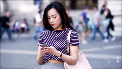 Portrait-of-a-young,-attractive-chinese-woman-using-smartphone-in-the-city