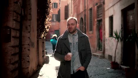 Portrait-of-young-handsome-man-looking-at-camera.-Happy-smiling-male-standing-in-morning-street,-drinking-coffee