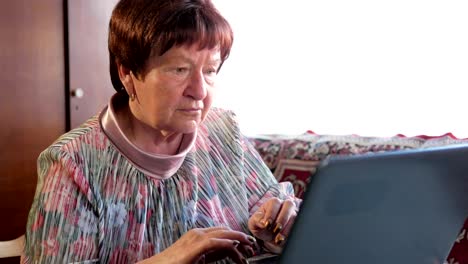 An-older-woman-checks-the-messages-on-social-networks-on-a-laptop-at-home.-She-sits-at-the-table