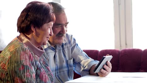 An-elderly-couple-communicates-with-their-grandchild-by-video-linking-the-tablet.-A-man-and-a-woman-are-talking-to-relatives