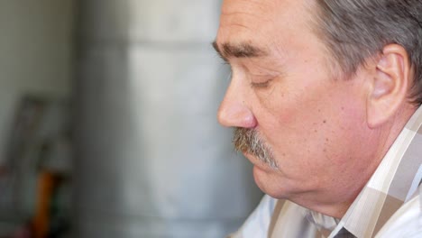 An-elderly-man-with-a-mustache-sits-behind-a-laptop-and-solves-problems.-He-looks-seriously-at-the-monitor