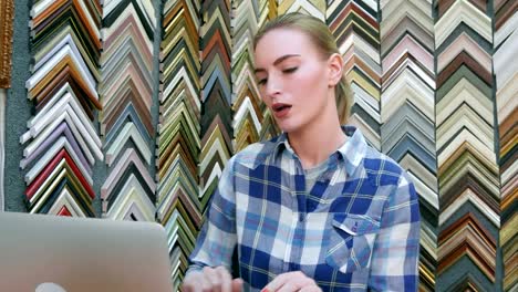 Portrait-of-a-young-female-business-owner-behind-the-counter-using-laptop-computer-in-her-shop