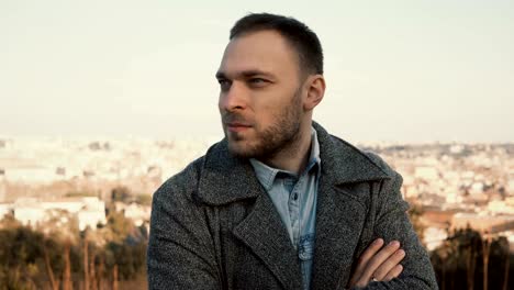 Young-handsome-man-standing-on-the-panoramic-view-of-Rome,-Italy-and-looking-around.-Serious-male-outside-in-sunny-day