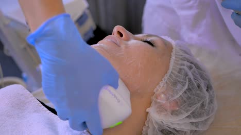 Cosmetologist-cleans-a-woman's-face-with-electronic-equipment