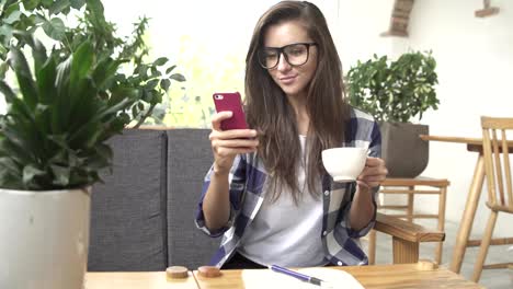 Mujer-utilizando-la-aplicación-smartphone-en-café-beber-café-y-risa