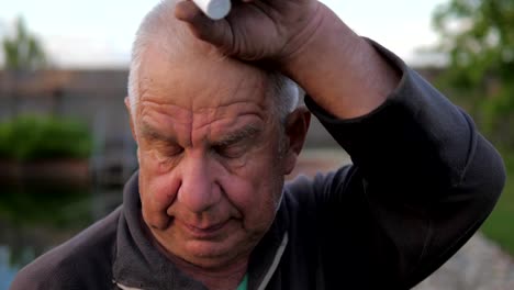 Portrait-of-an-elderly-man,-wiping-his-hand-with-sweat-from-his-forehead.