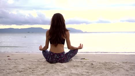 Yoga-meditating-in-lotus-pose-on-beach.