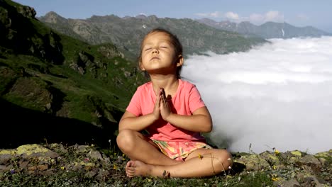 Little-cute-girl-meditating-on-top-of-mountain