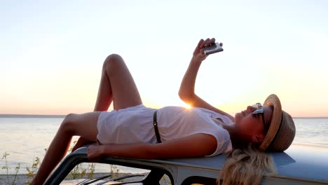 Feliz-viaje,-joven,-acostado-en-el-auto-de-la-azotea-hace-fotos-en-teléfono,-mujer-hacer-foto-selfie-en-móvil-en-el-coche-retra