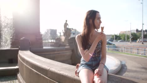 Mujer-hermosa-joven-comer-helado-durante-el-día-soleado,-al-aire-libre.