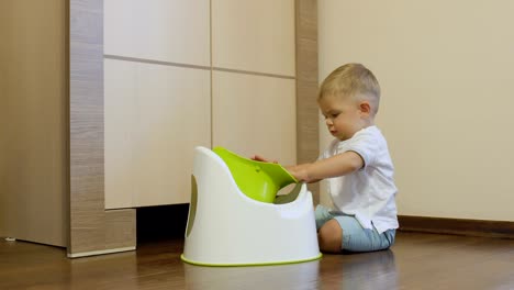 Golden-haired-boy-plays-with-his-potty