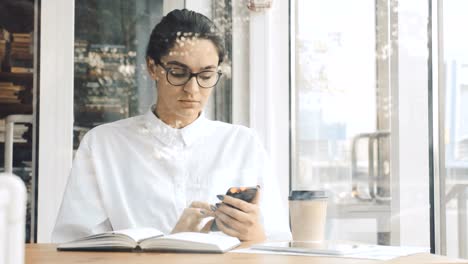 Young-woman-using-phone-and-making-notes