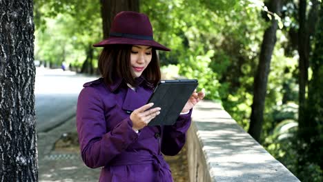 lächelnde-anspruchsvolle-chinesische-Frau-mit-Tablet-in-der-Straße,-Porträt