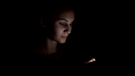 Closeup-view-of-a-woman-using-her-phone-in-a-dark-room,-chatting-in-the-darkness-with-smartphone,-communicating-with-friends-online