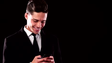 A-smiling-guy-in-a-suit-is-typing-something-in-his-phone