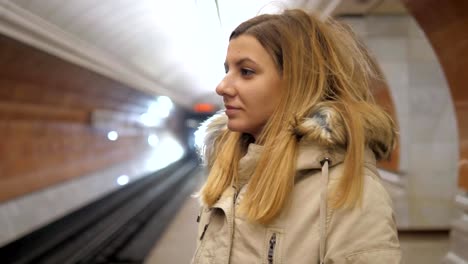 Attractive-woman-standing-in-metro-and-using-the-smartphone,-waiting-a-train.