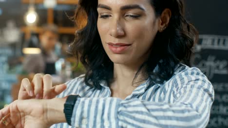 Hermosa-mujer-comprobar-mensajes-en-su-Smartwatch.-Ella-está-en-la-tienda-de-café-busca-moderno.