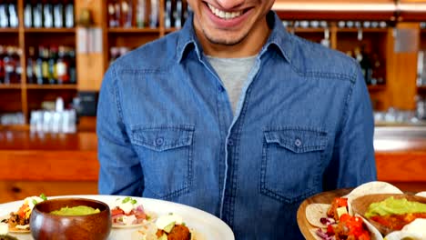 Waiter-holding-plate-of-mexican-food-in-bar-4k