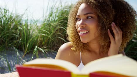 Portrait-of-voluptuous-Ethnic-female-reading-on-beach