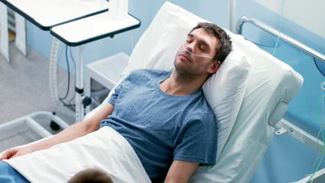 En-el-Hospital-enfermo-paciente-masculino-duerme-en-la-cama,-lleva-una-cánula-Nasal.-Enfermera-entra-y-comprueba-su-contador-de-la-gota,-aumenta-la-dosis-de-dolor-asesino.