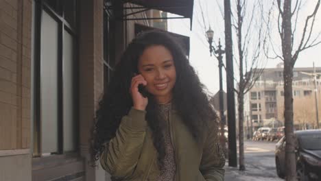 Medium-shot-of-a-beautiful-young-woman-walking-through-the-city-while-talking-on-her-phone