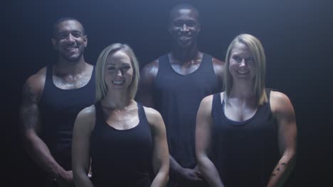 Group-of-athletes-smiling-and-laughing-at-the-camera-on-a-dark-background